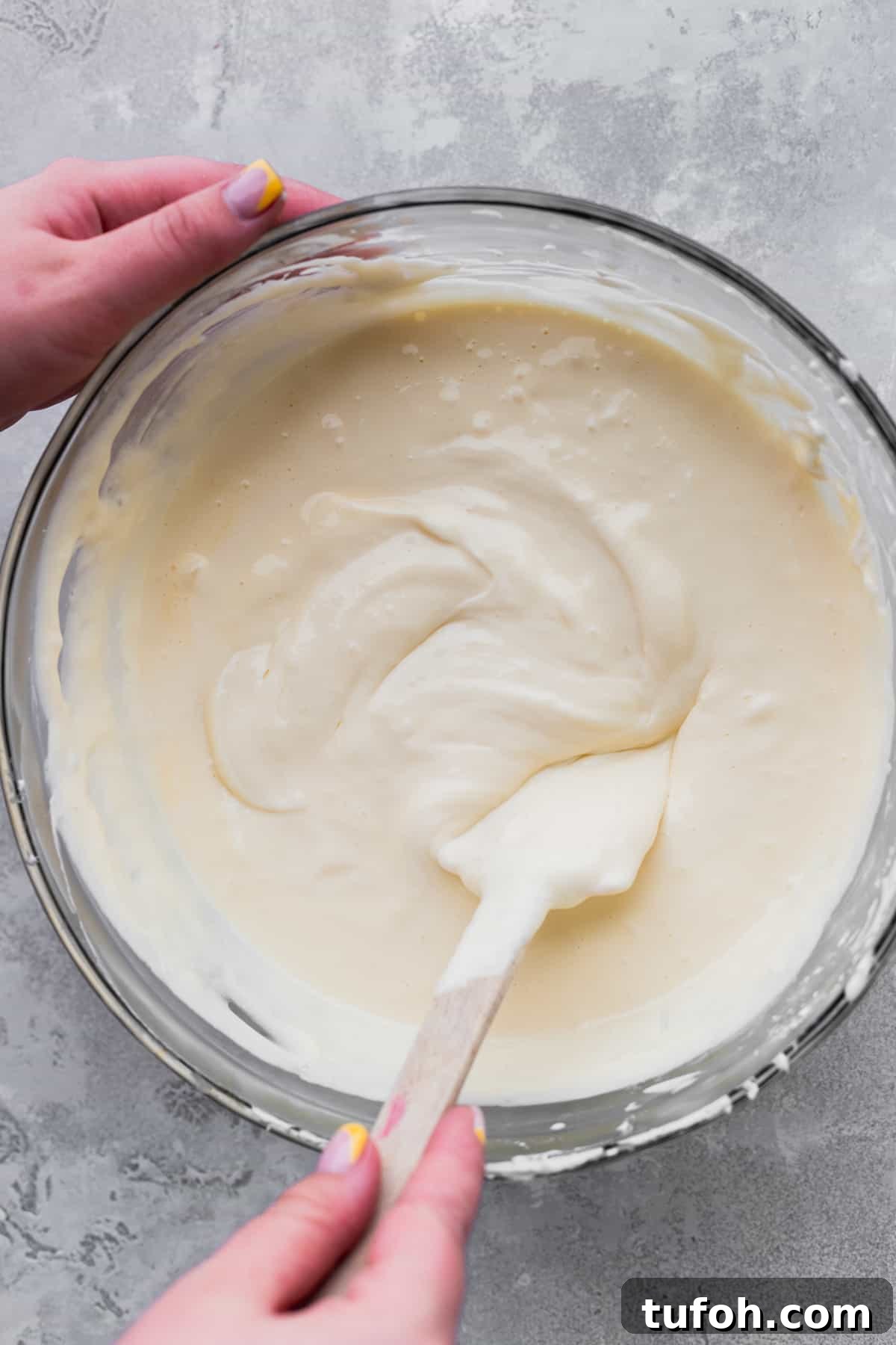 Decadent Honey Cheesecake Recipe with Silky Cream Filling 7 Cheesecake batter with a rubber spatula stirring it.