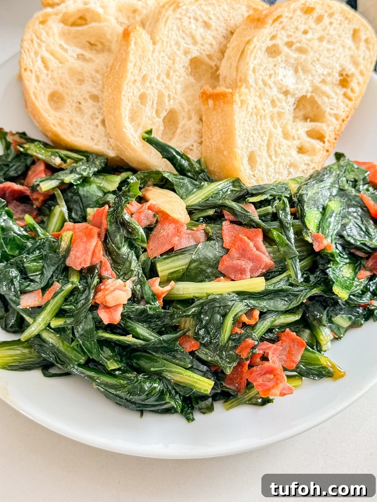 A close up image of spicy dandelion greens on a plate with some bread slices in the background.