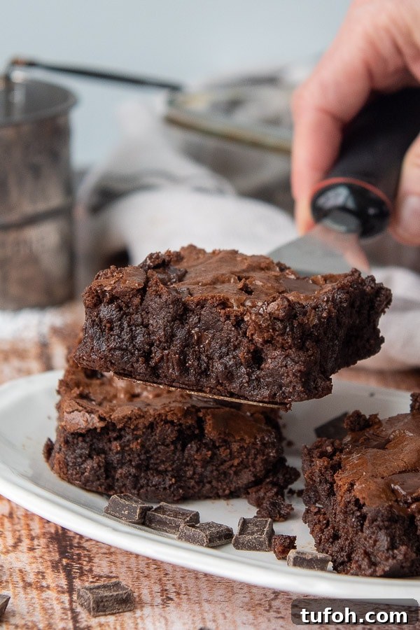 Ultra-Fudgy Almond Flour Chocolate Brownies 9 a spatula holding up an brownie