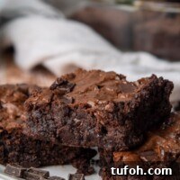 Ultra-Fudgy Almond Flour Chocolate Brownies 10 a stack of three brownies on a white plate