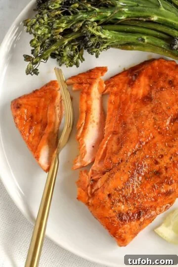 A gold fork cutting into a salmon fillet.