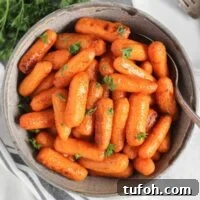 Air fried roasted baby carrots in a gray serving bowl with a serving spoon.