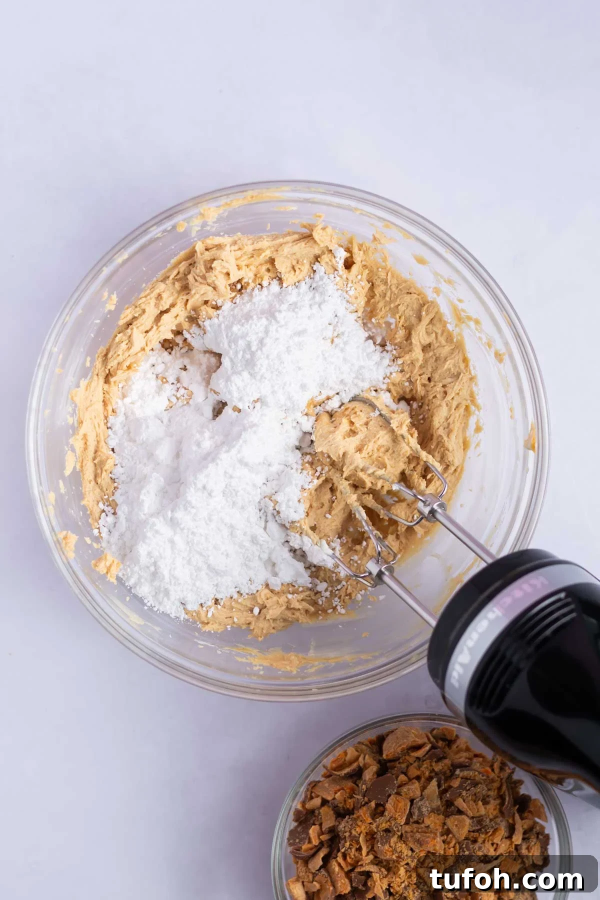 confectioners' sugar added to cream cheese and peanut butter in a mixing bowl