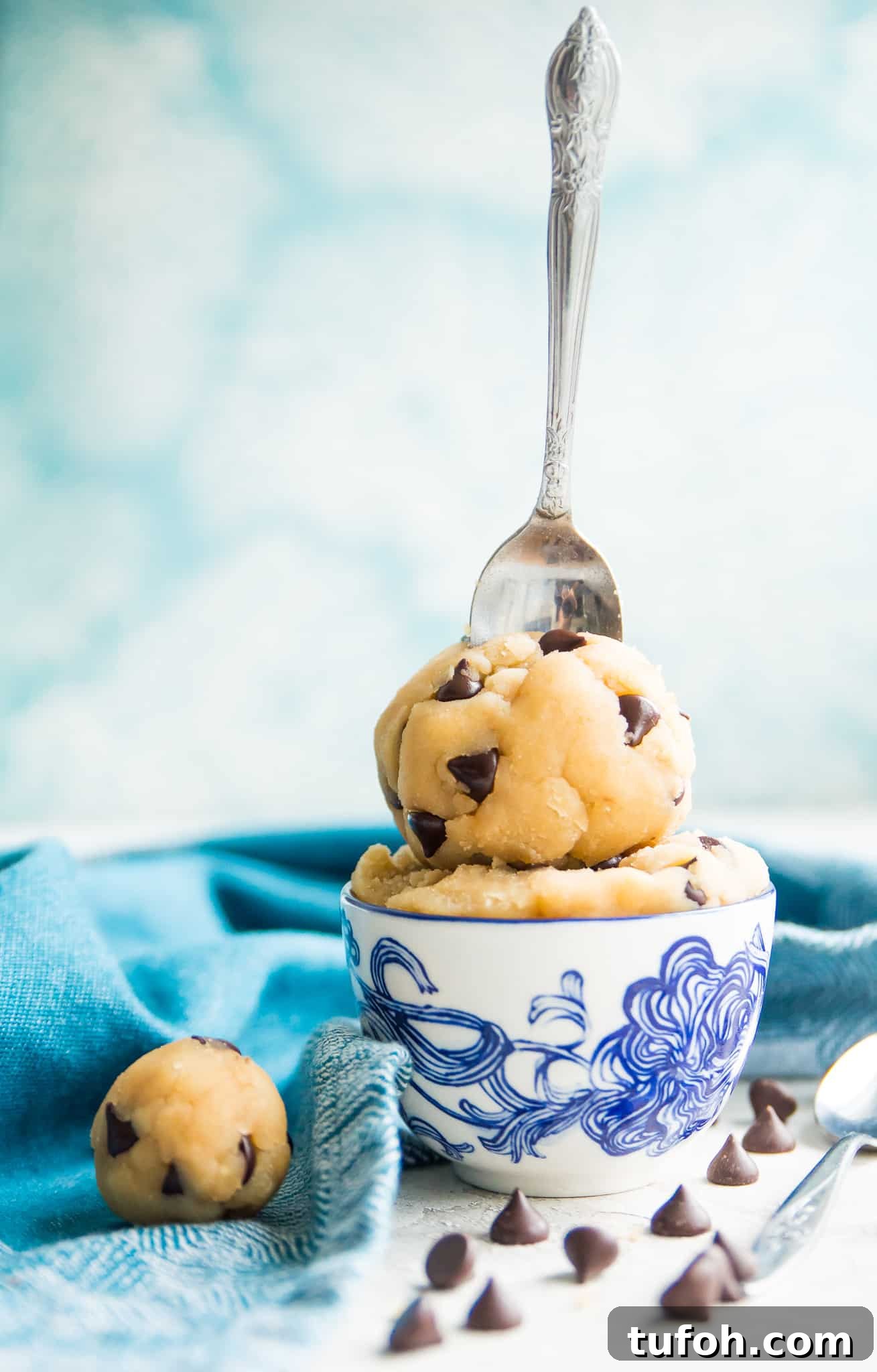 A bowl of edible chocolate chip cookie dough with a spoon in it.