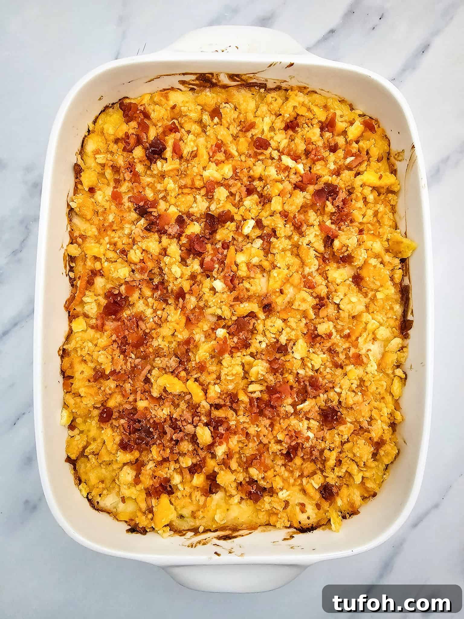 Creamy Cheesy Potato Casserole 9 Baked cheesy casserole with a golden, crispy topping in a white dish on a marble surface.