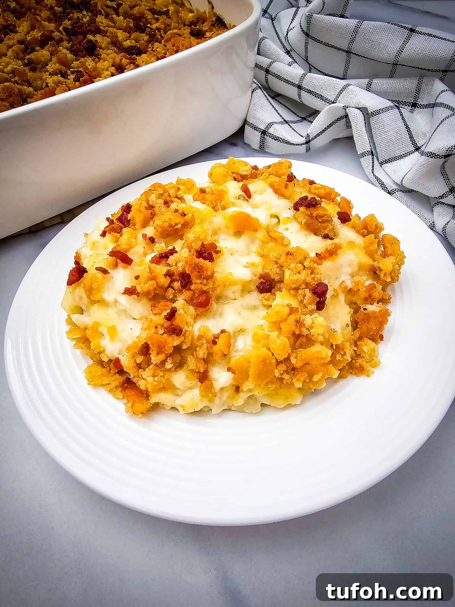 Creamy Cheesy Potato Casserole 10 A serving of baked macaroni and cheese casserole with a crunchy topping on a white plate.
