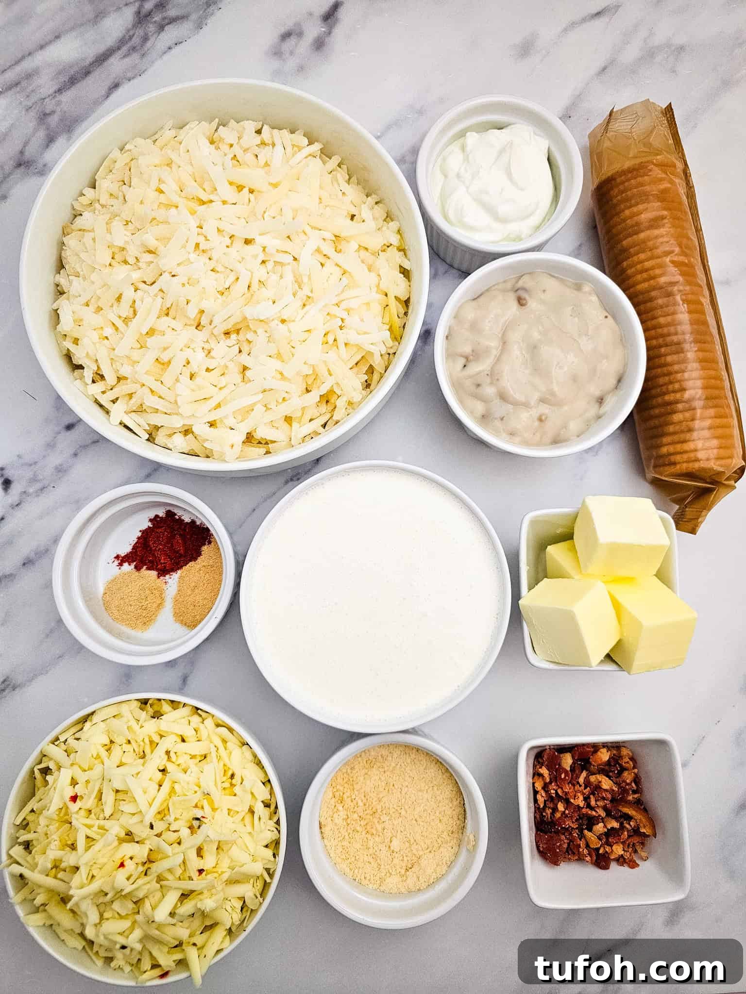 Creamy Cheesy Potato Casserole 4 Bowls of shredded potato, cheese, butter, cream, seasonings, crackers, bacon, and sour cream on marble—perfect for assembling a comforting casserole.