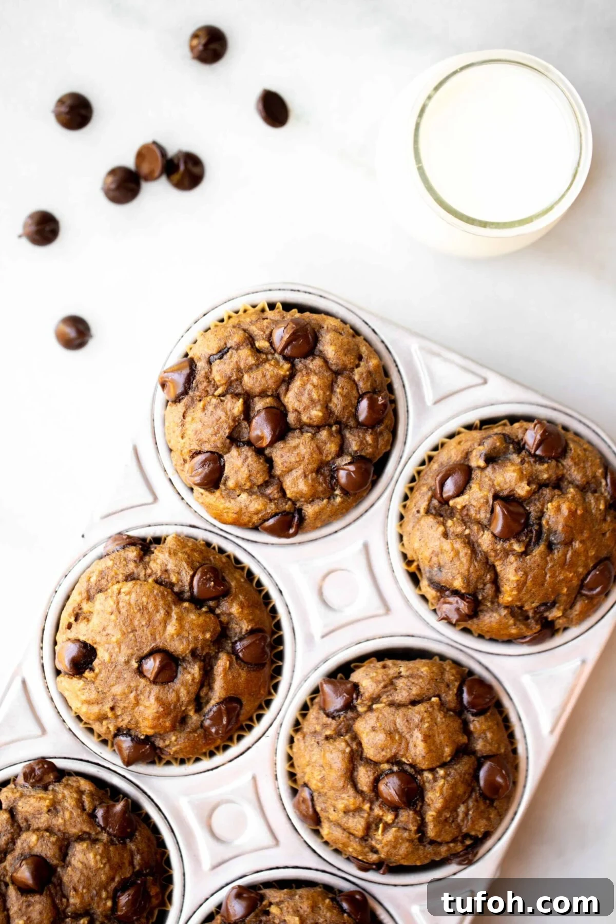 Banana Lentil Muffins: Protein-Packed Breakfast Muffin Recipe 4 overhead photo of freshly baked chocolate chip banana muffins in an aluminum muffin pan with milk and chocolate chips in the background