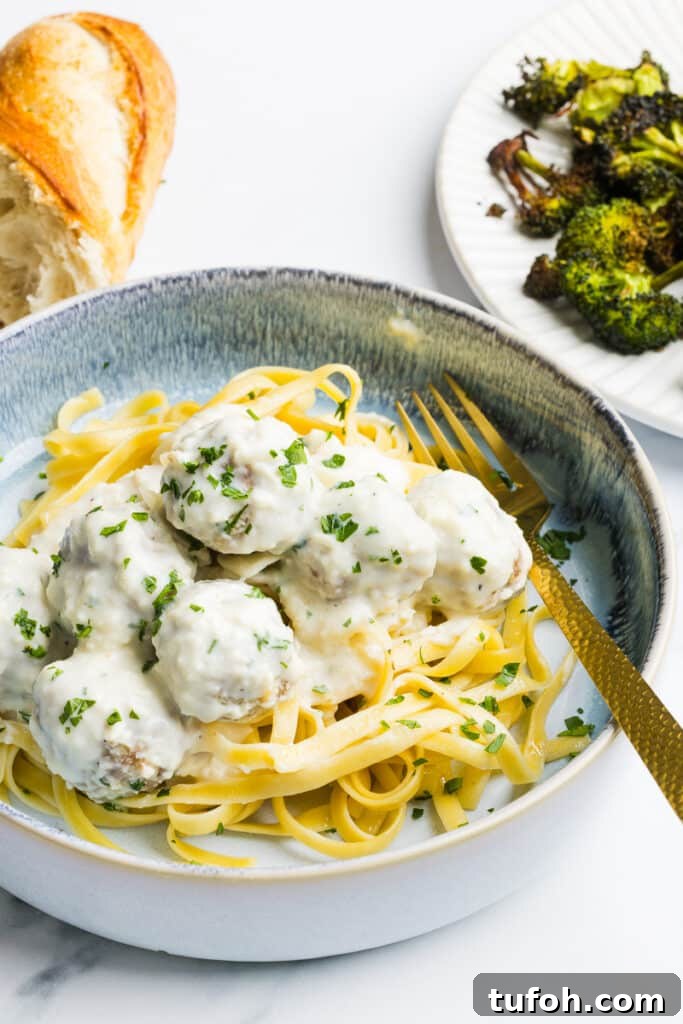 Greek Yogurt Alfredo Meatballs with Creamy Parmesan Sauce 4 Alfredo meatballs on a plate with pasta and garnished with parsley.