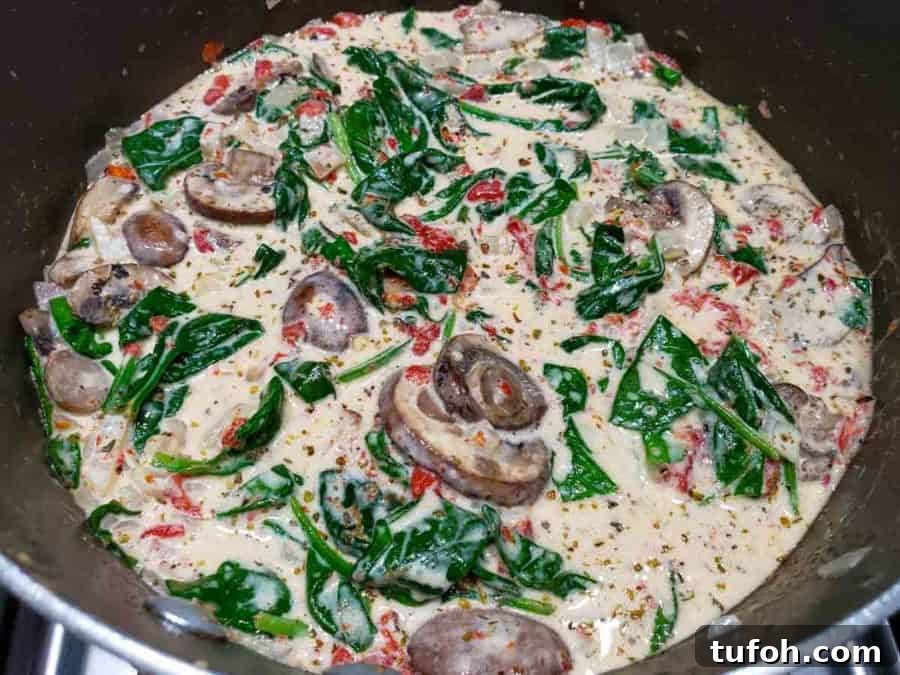 Tuscan Garlic Shrimp with Creamy Orzo 6 a pan filled with mushrooms, roasted red peppers, spinach and onions in a yellow butter sauce