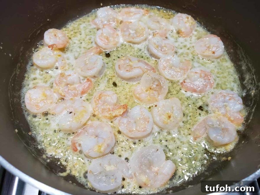 Tuscan Garlic Shrimp with Creamy Orzo 3 pink shrimp cooking in a yellow butter sauce