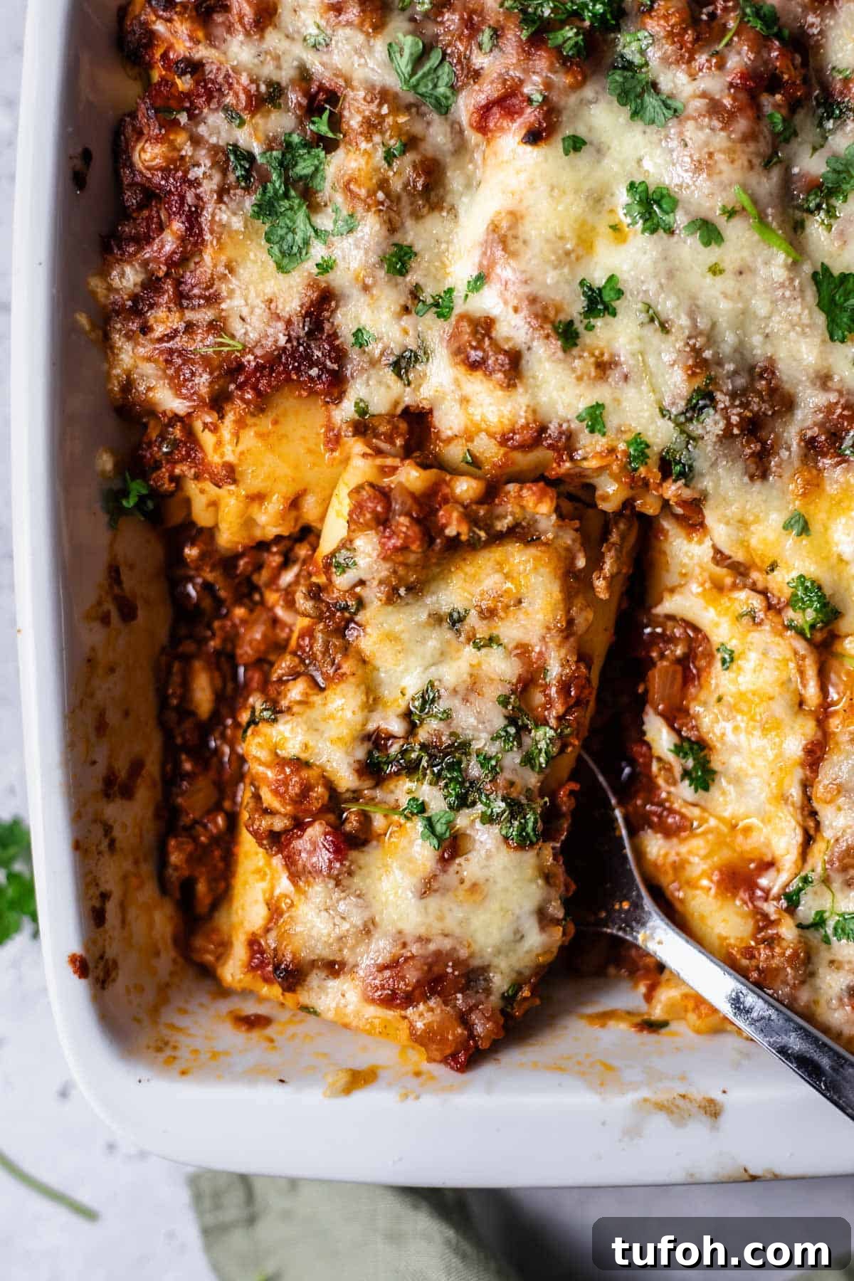 Cheesy Baked Lasagna Rolls with Marinara and Ricotta 10 a baked lasagna roll being lifted up with a serving spoon