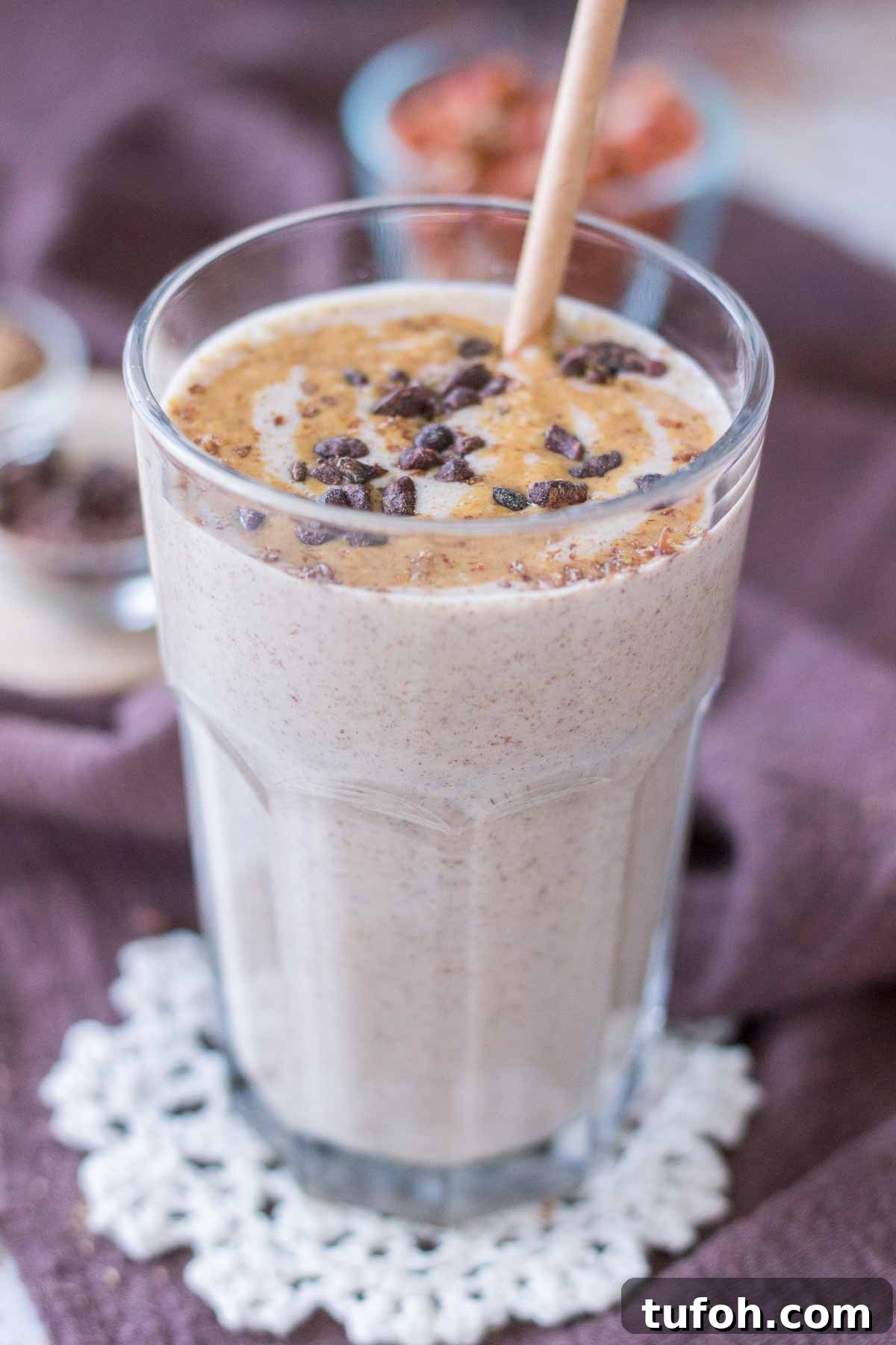 Close up of a Peanut Butter Protein Shake in a glass topped with peanut butter and chocolate with a straw