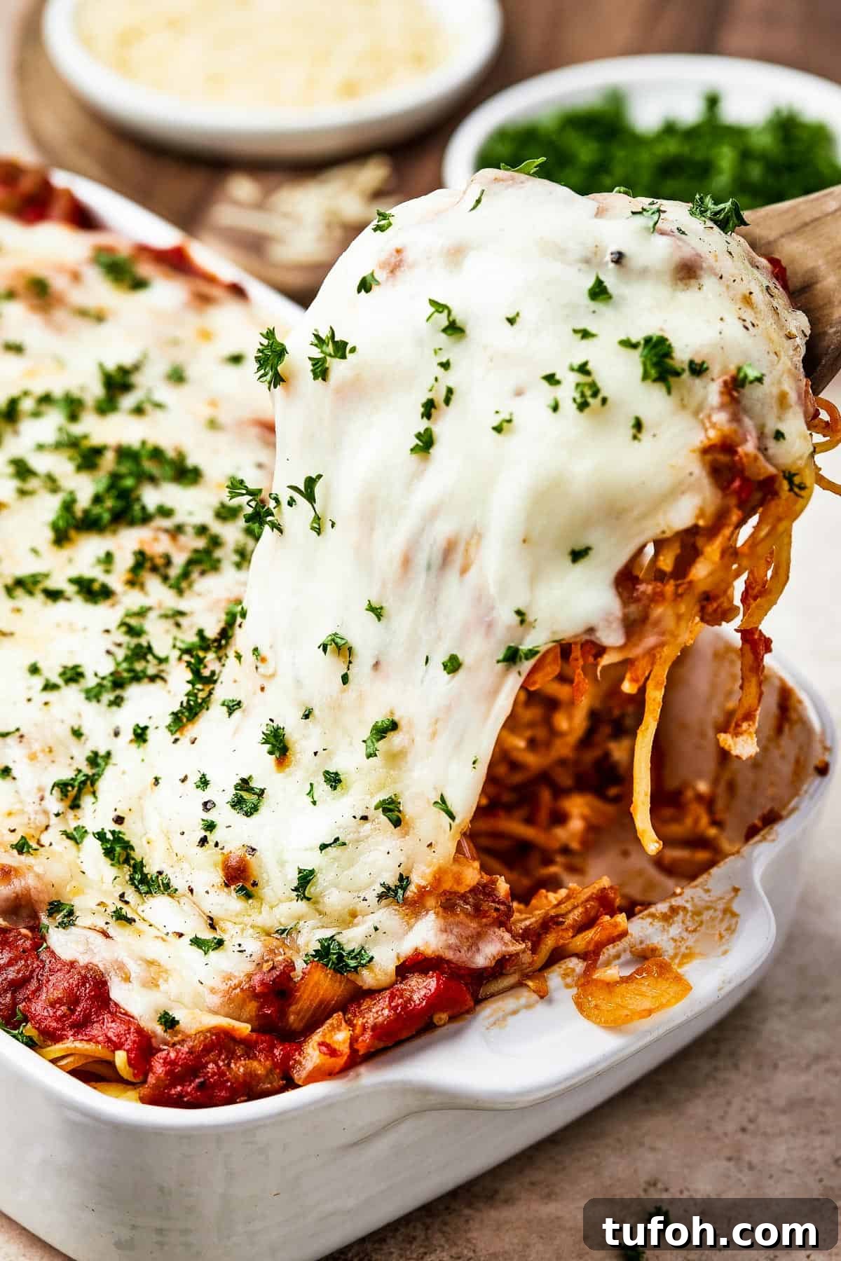 Ultimate Cheesy Baked Spaghetti Casserole Recipe 2 A portion of spaghetti bake being lifted from a casserole dish, with the cheese topping stretching.