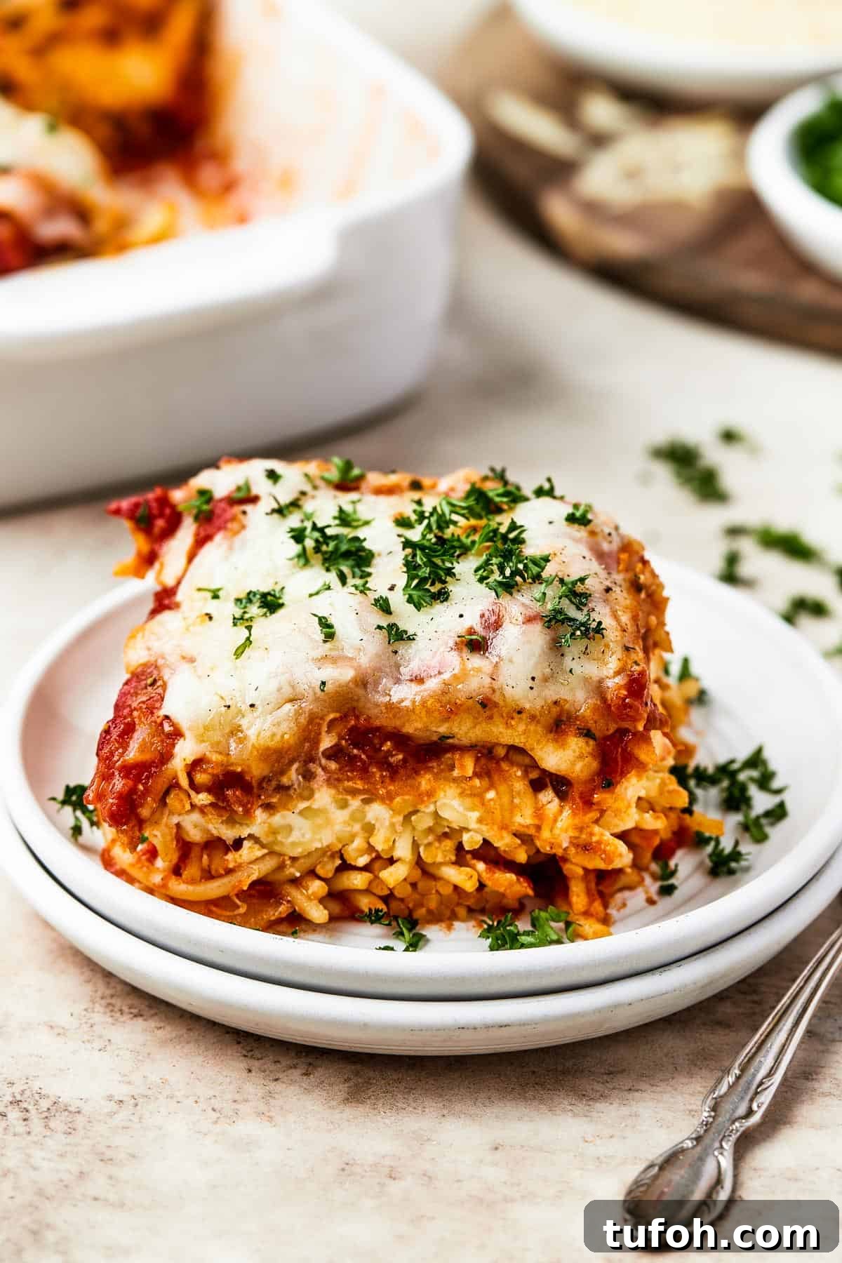 Ultimate Cheesy Baked Spaghetti Casserole Recipe 3 A square of baked spaghetti on a plate.