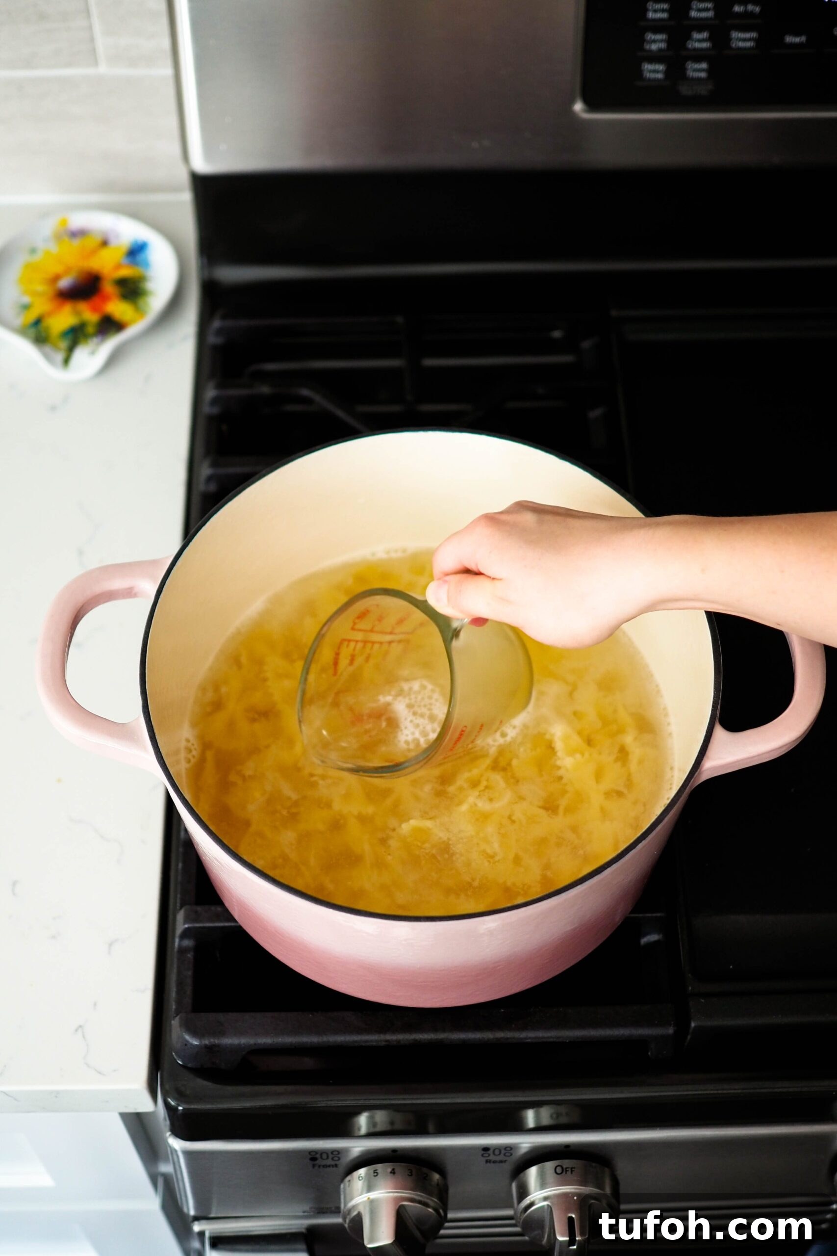 Creamy Cajun Spinach Pasta for Two: Quick Weeknight Recipe 5 Dipping a glass measuring cup into pasta water.