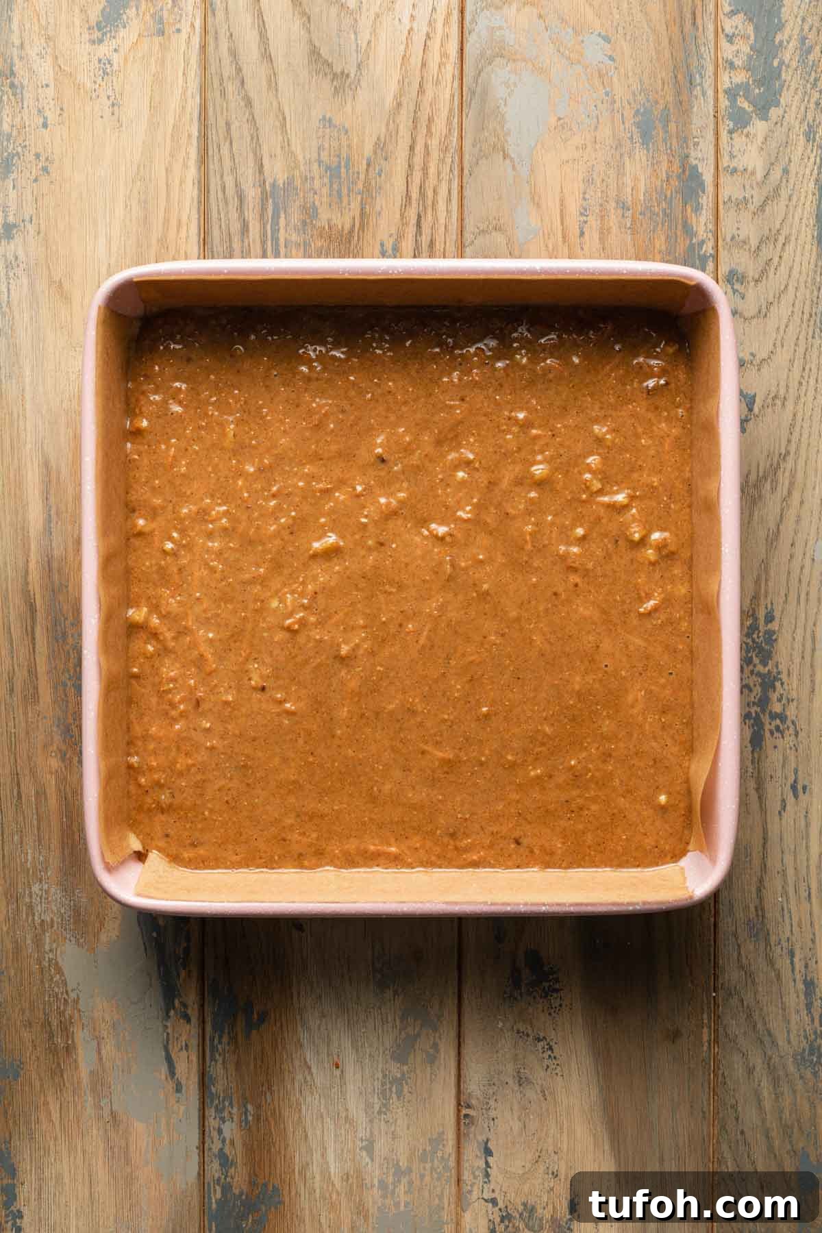 Carrot cake batter in a pink square baking pan.