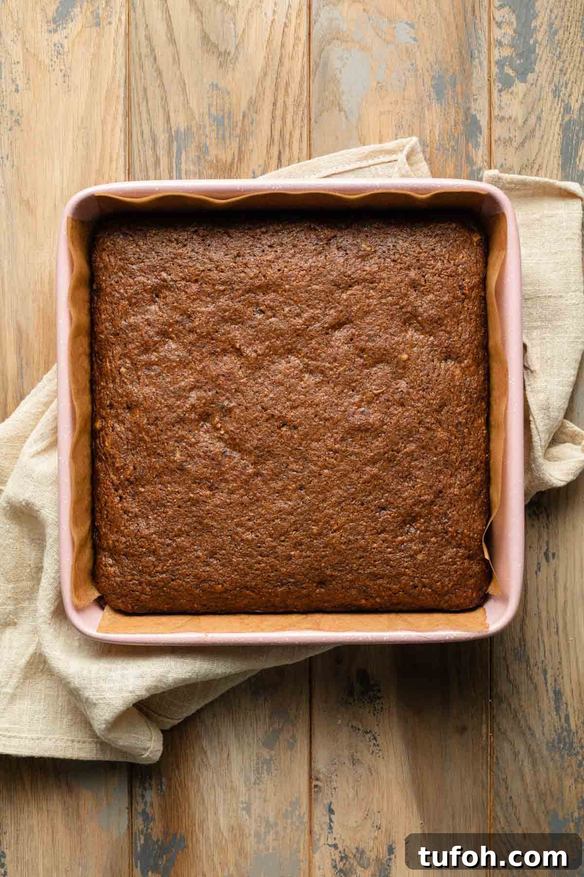 Carrot cake cooling in a pink square baking pan.