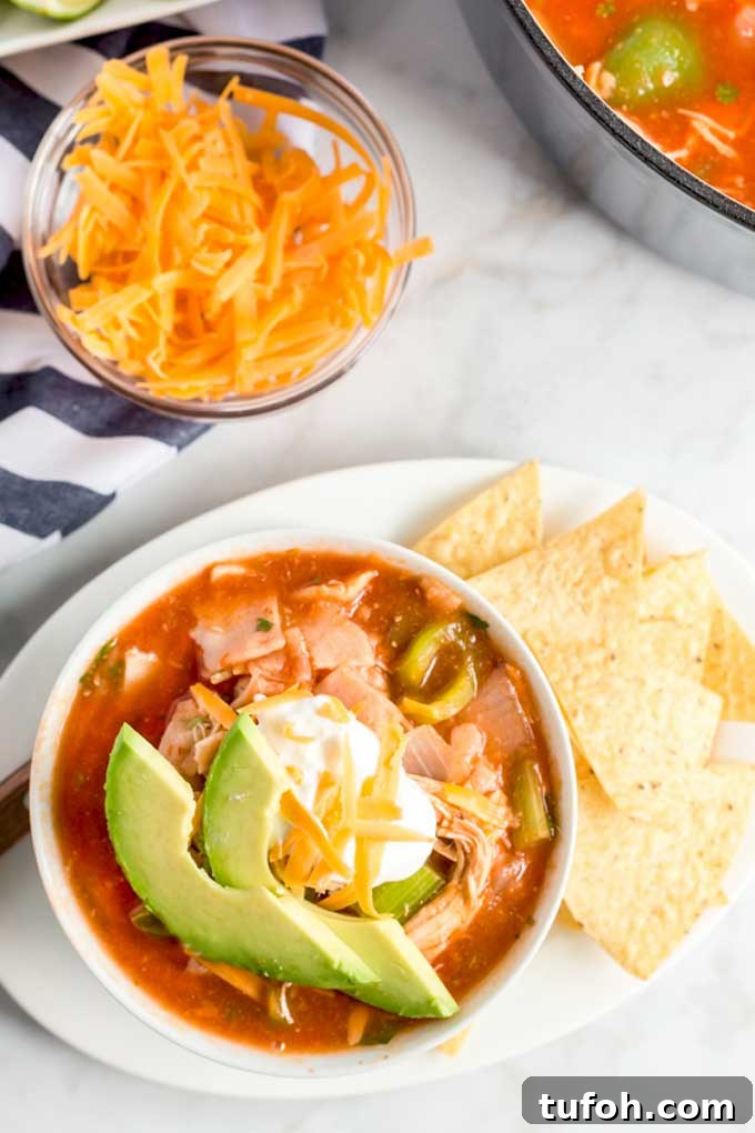 Comforting Chicken Tortilla Soup with Avocado and Crispy Tortillas 3 Top view of a bowl with Chicken Tortilla soup topped with shredded cheese, sour cream and avocado sices