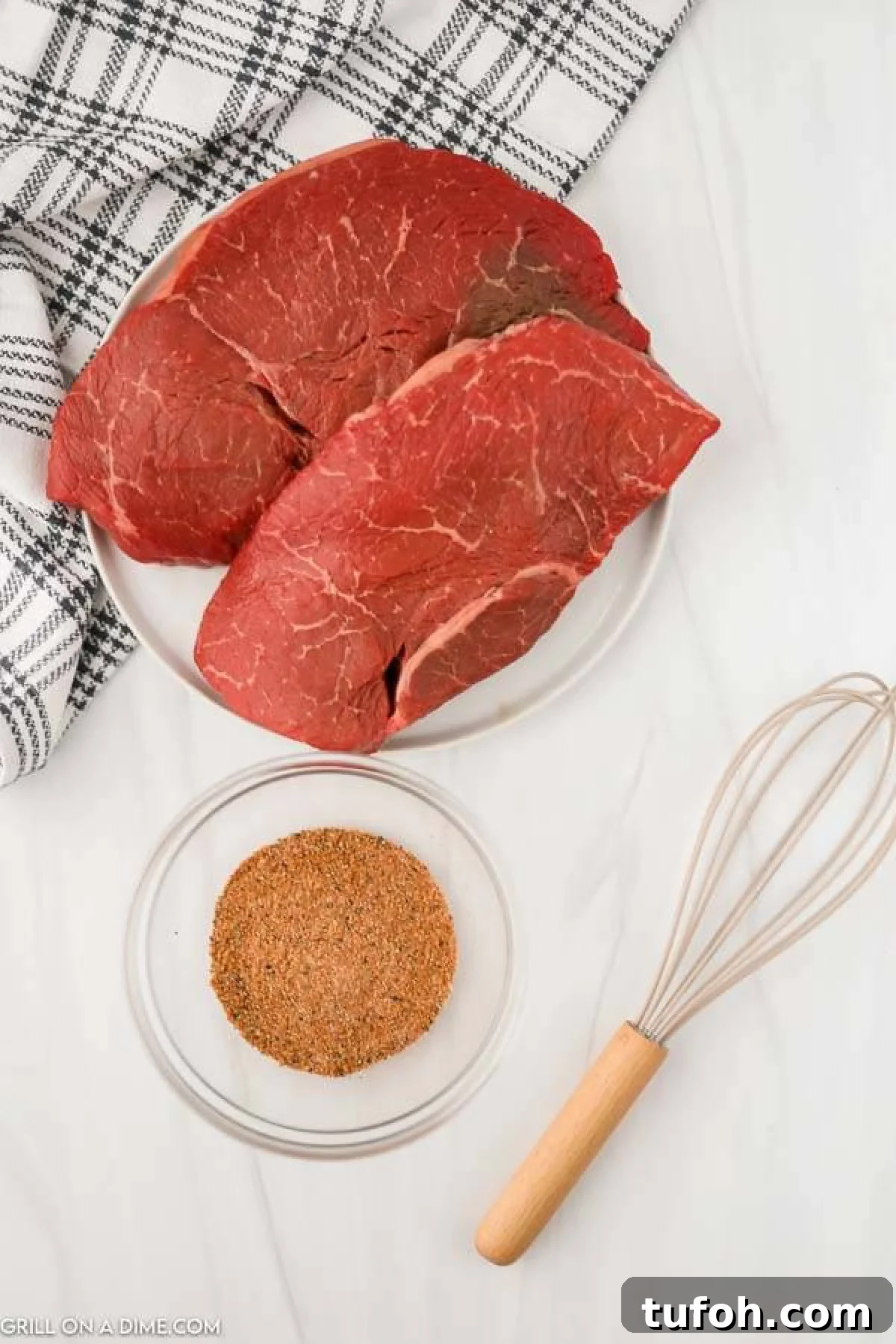 Uncooked steak on a plate with a small bowl of seasoning blend.