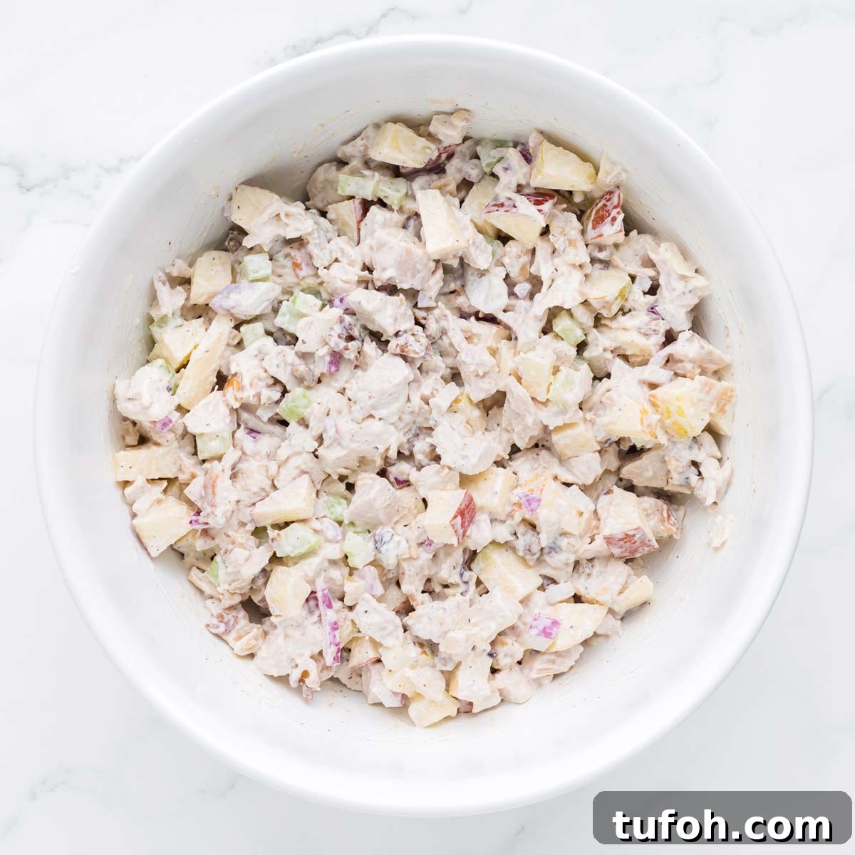 adding the apple walnut chicken salad to a large bowl