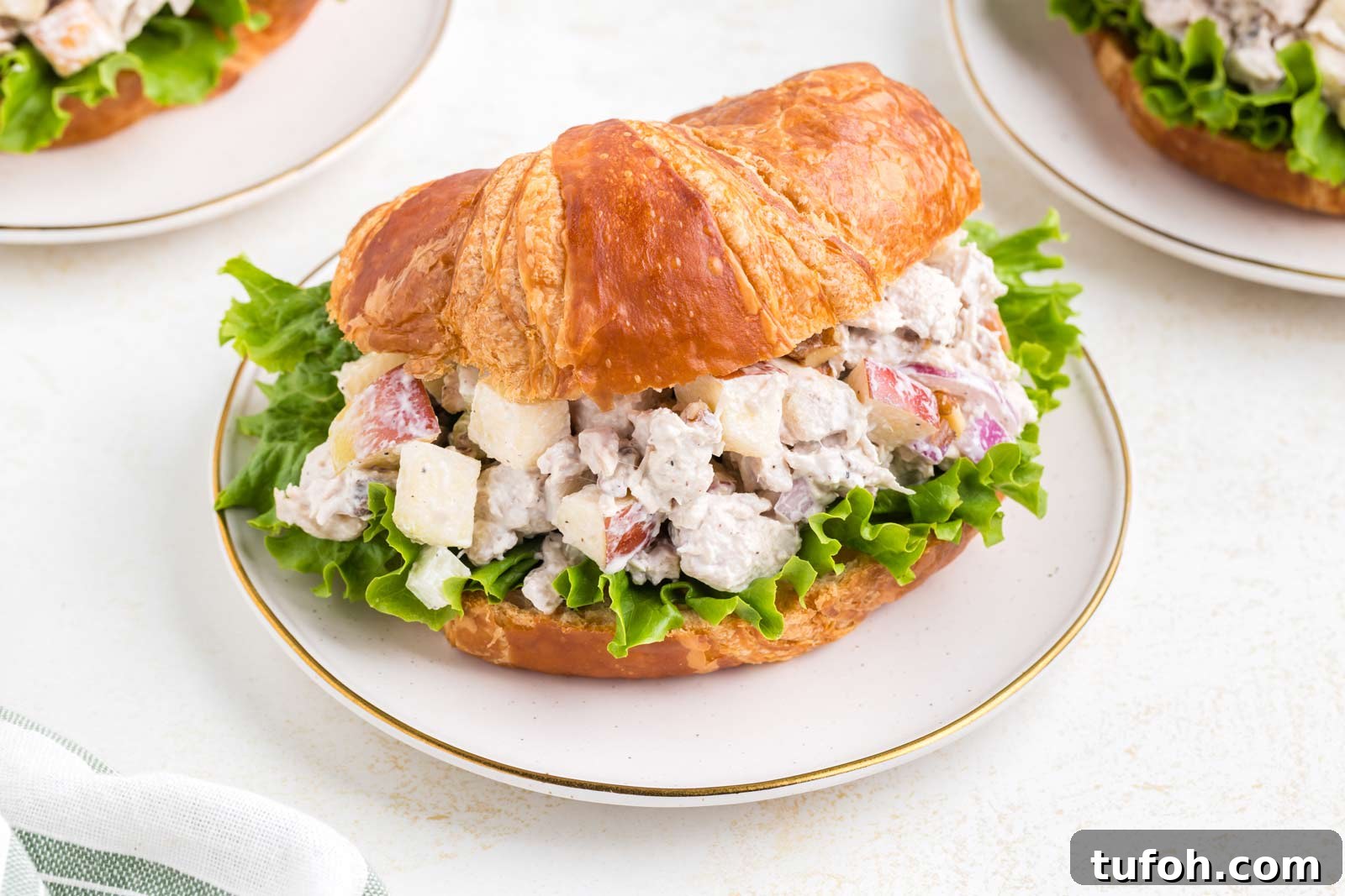 apple walnut chicken sandwich in a croissant on a white table