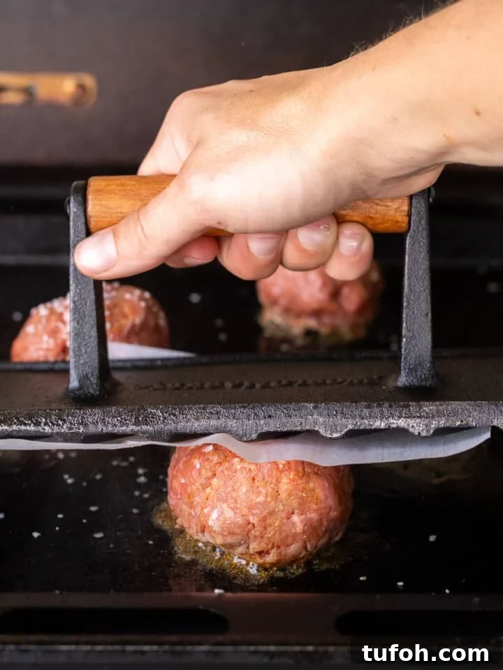 Caramelized Onion Smash Burger — Next-Level Flavor 11 hand using a grill press to smash a burger patty