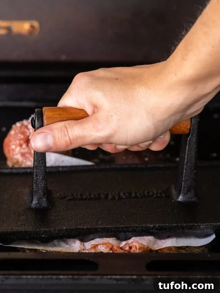 Caramelized Onion Smash Burger — Next-Level Flavor 12 hand using a grill press to fully smash a burger patty