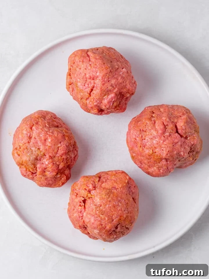 Caramelized Onion Smash Burger — Next-Level Flavor 6 four balls of ground beef on a plate