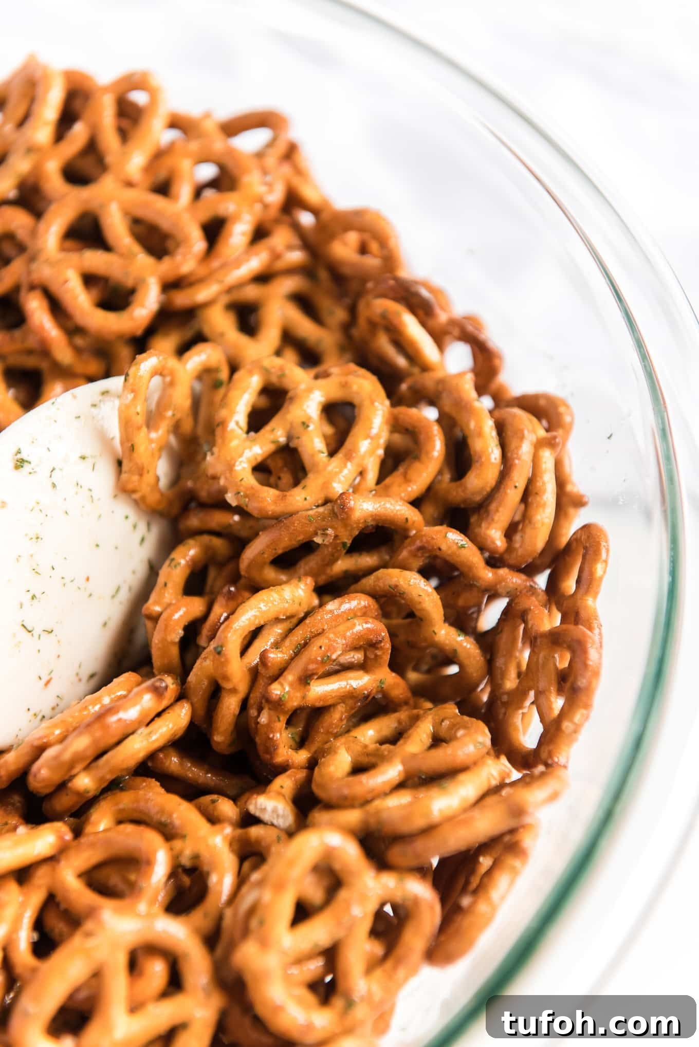 Crunchy Ranch Pretzel Bites: Savory Snack Recipe 5 Mixing the ranch pretzels in a bowl with a rubber scraper.