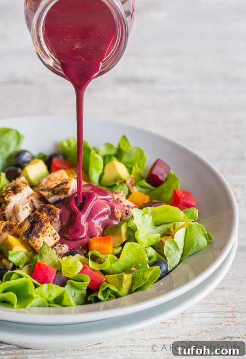 Pouring blueberry vinaigrette on the chicken salad.