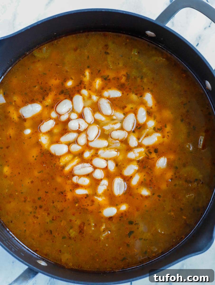 White beans being added to a pot of soup.