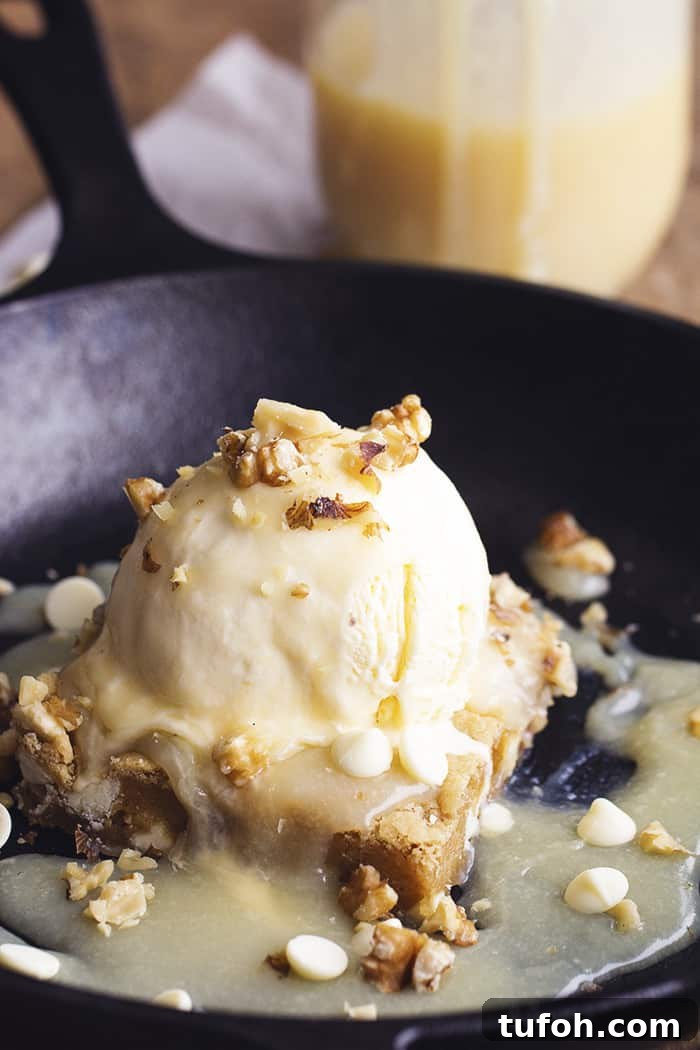White chocolate blondies served warm with maple cream sauce. white chocolate blondie in a black skillet.