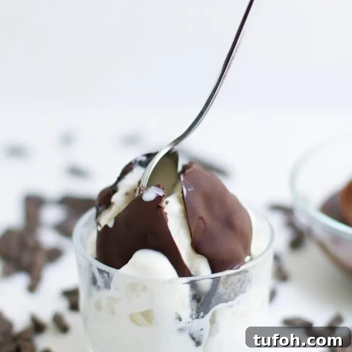 A close up view of Chocolate hard shell ice cream topping cracked open with a spoon on a scoop of vanilla ice cream from themerchantbaker.com
