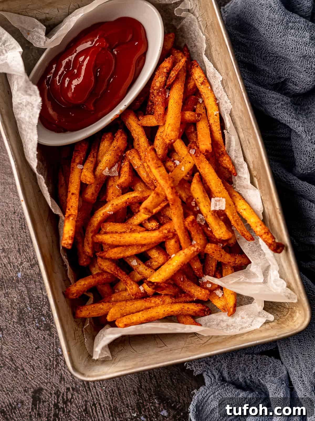 Fries in a parchment paper lined container with a side of ketchup