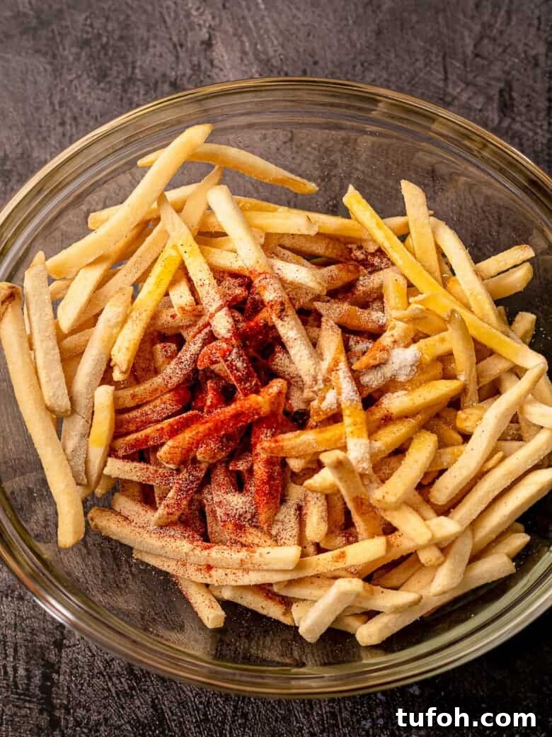 A glass bowl filled with fries and topped with spices.