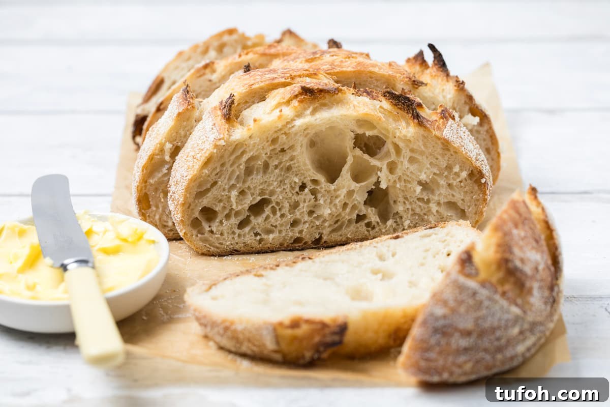 Small-Batch Sourdough Loaf Recipe for Home Bakers 2 Rustic small batch sourdough bread loaf sliced open on parchment paper with butter and fresh bread slices nearby.