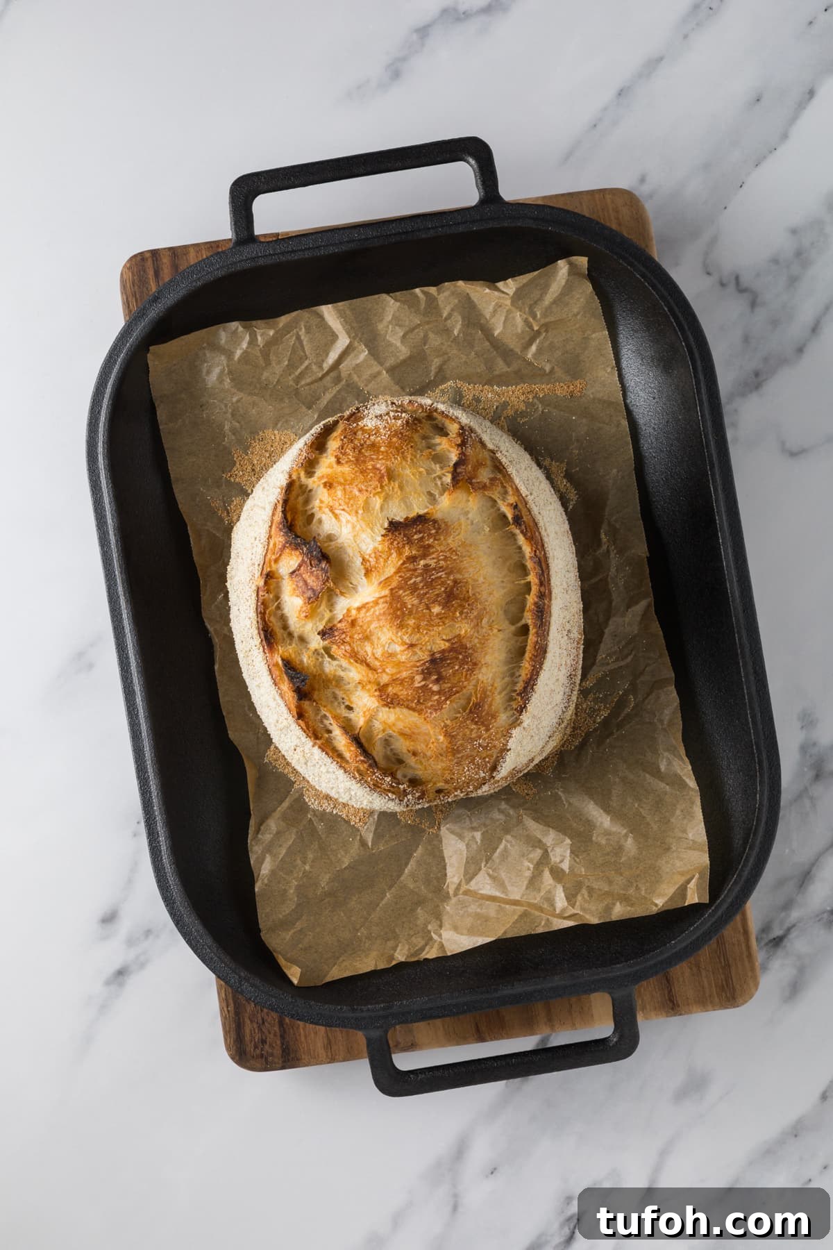 Small-Batch Sourdough Loaf Recipe for Home Bakers 12 Freshly baked small batch sourdough bread loaf in a cast iron roasting pan lined with parchment paper.