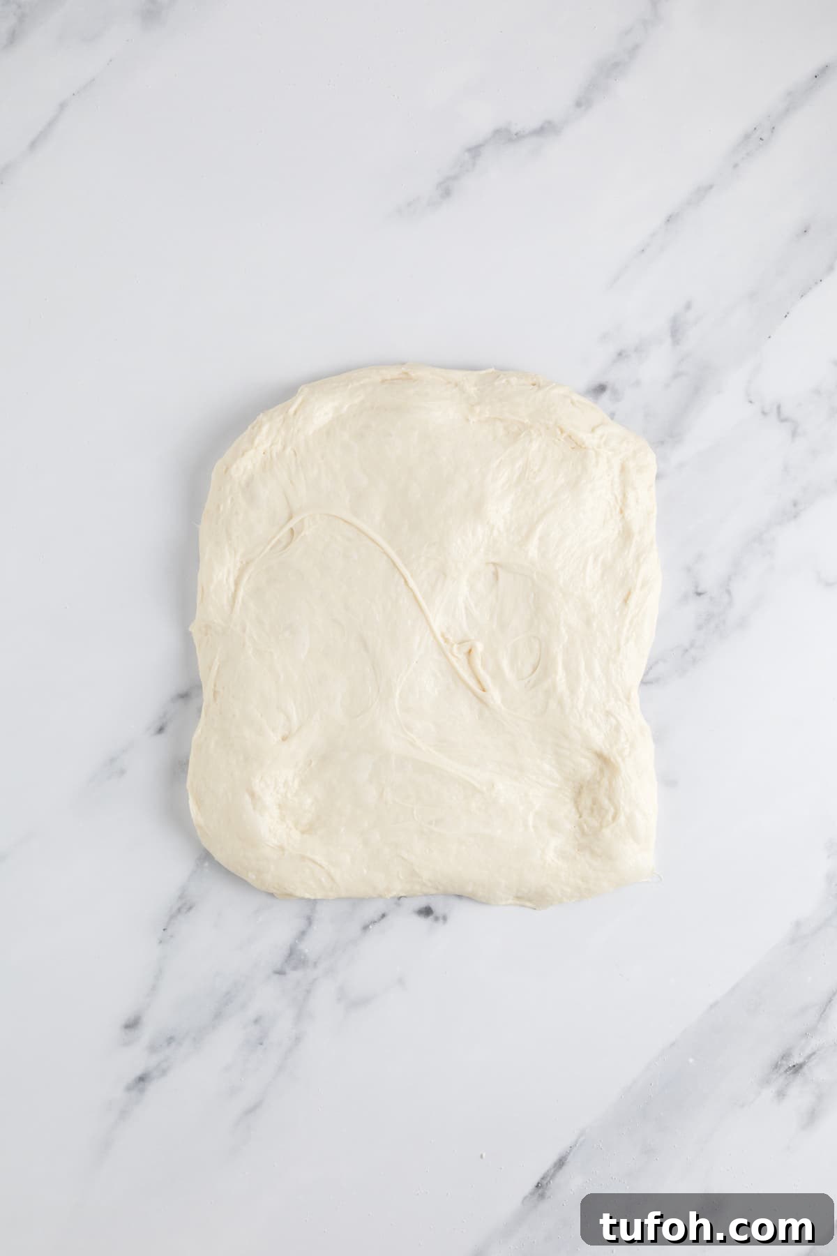 Small-Batch Sourdough Loaf Recipe for Home Bakers 9 Small batch sourdough bread dough stretched flat during shaping before forming into a loaf.