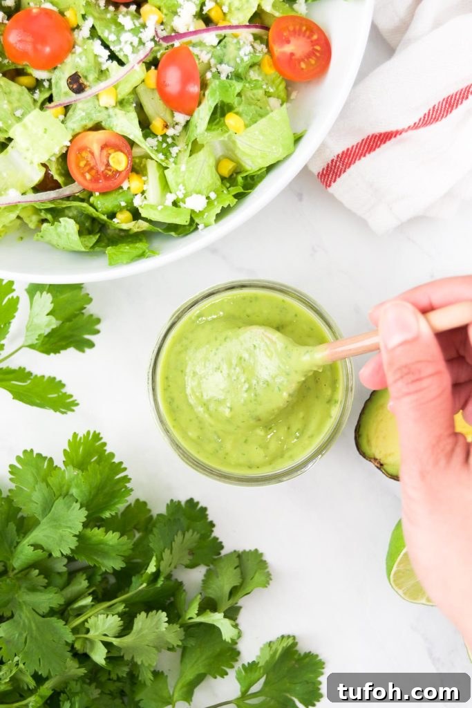Creamy Avocado Lime Dressing Recipe for Salads & Bowls 2 A woman stirs a container of lime avocado dressing next to a bowl of salad