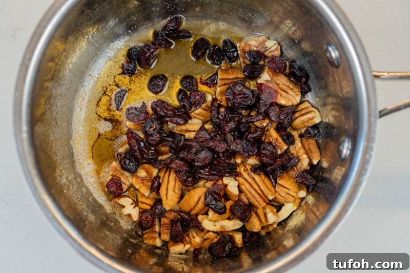 Adding pecans, cranberries and maple syrup to the pot