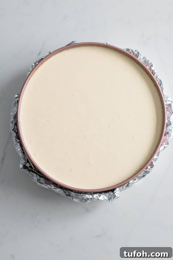foil wrapped around pan of cheesecake batter