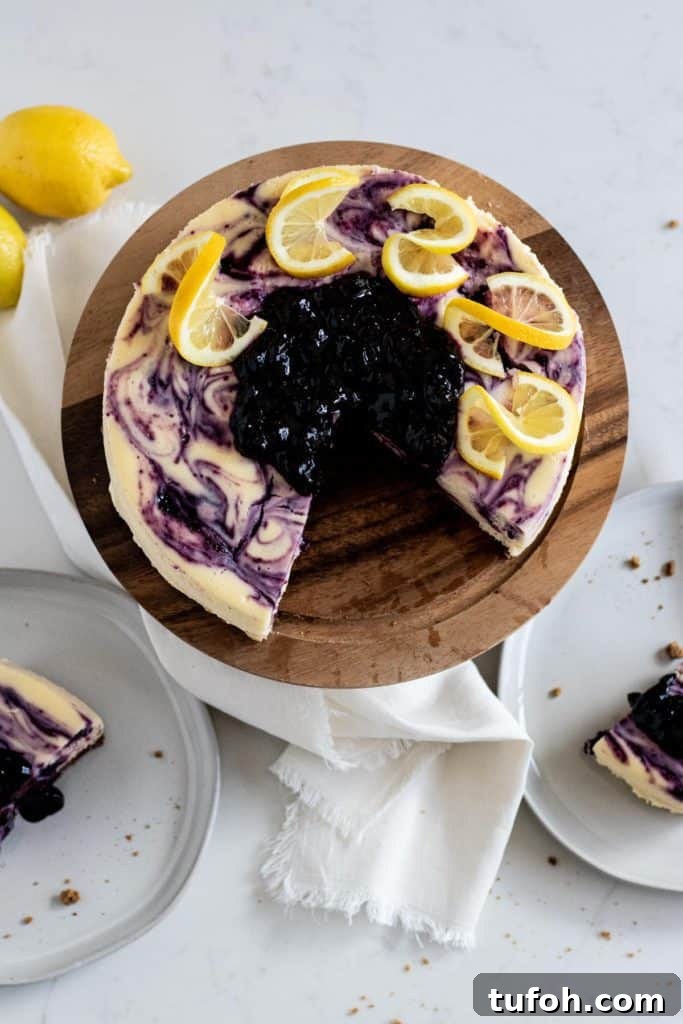 overhead view of whole lemon blueberry cheesecake and slices on a plate