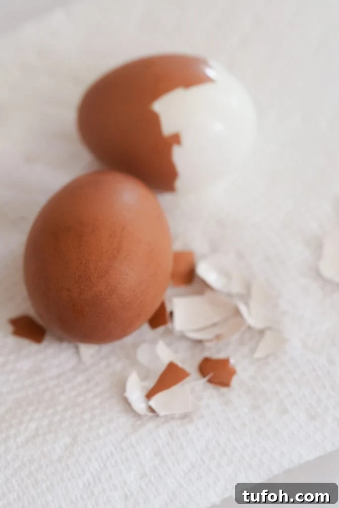 Perfect Jammy Eggs: Soft-Boiled Recipe for Runny Yolks 6 two boiled eggs on a paper towel, one partially peeled