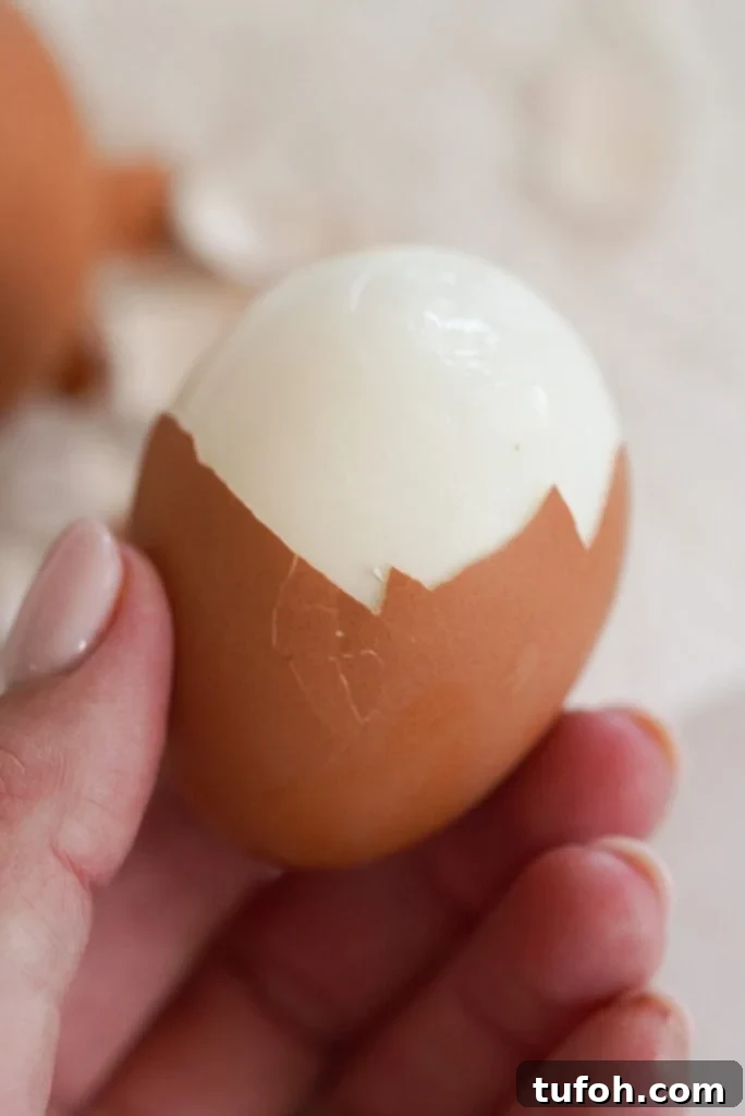 Perfect Jammy Eggs: Soft-Boiled Recipe for Runny Yolks 7 hand holding a halfway peeled soft boiled egg