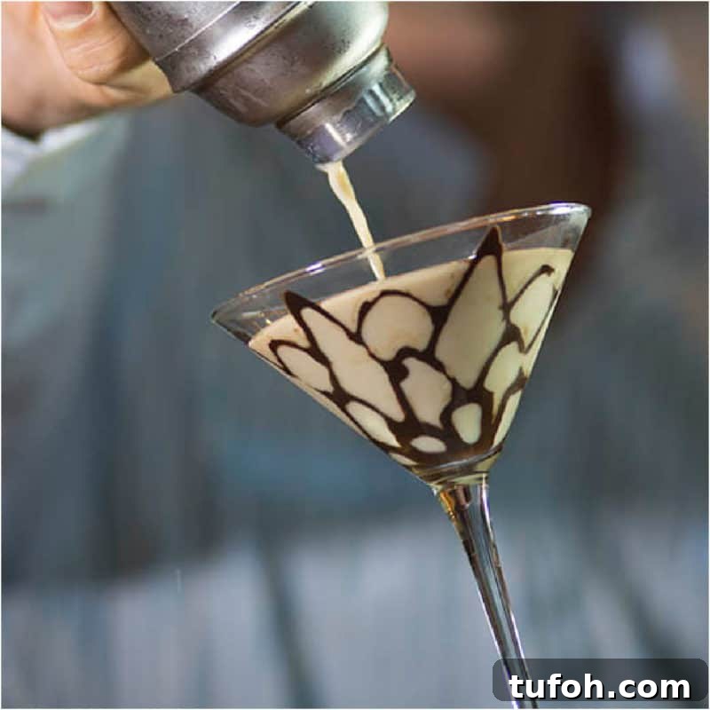 25+ Romantic Valentine's Day Cocktails and Toasting Drinks 13 Tiramisu Martini pouring from a cocktail shaker into a martini glass with chocolate design.