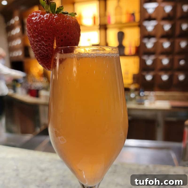 25+ Romantic Valentine's Day Cocktails and Toasting Drinks 15 champagne glass with drink garnished with a strawberry on the counter of the Alchemy Bar