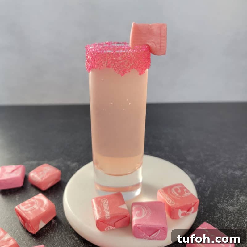 25+ Romantic Valentine's Day Cocktails and Toasting Drinks 18 Pink Starburst Shot on a white coaster surrounded by Starburst candies