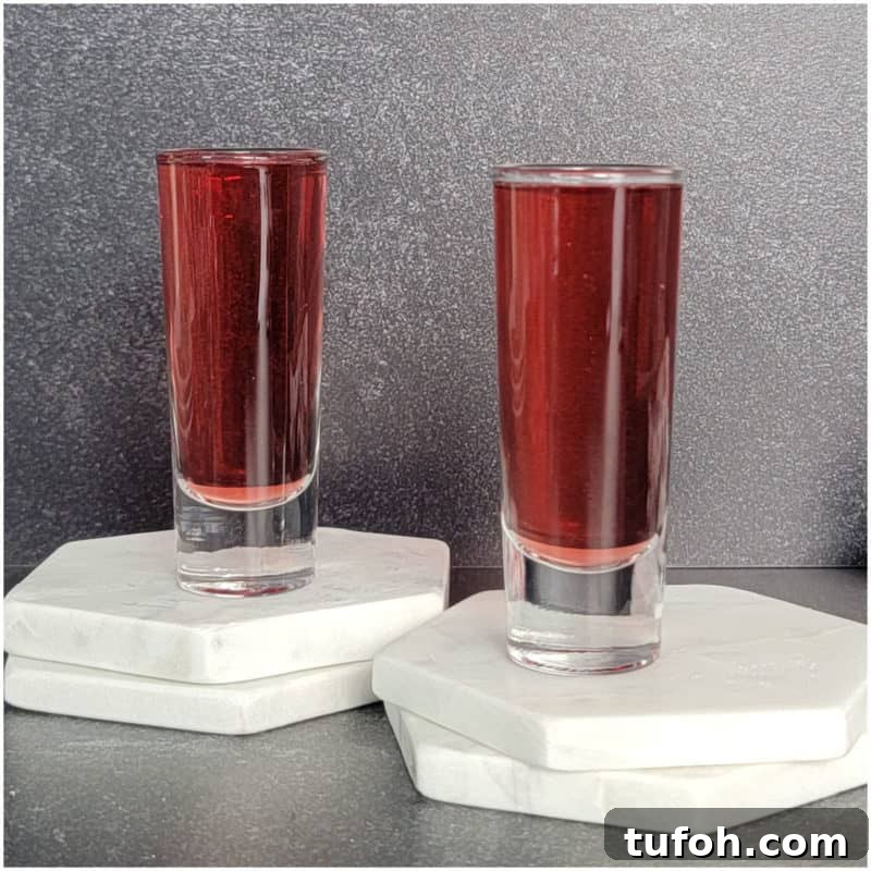 25+ Romantic Valentine's Day Cocktails and Toasting Drinks 21 Two red cocktail shots on white coasters.