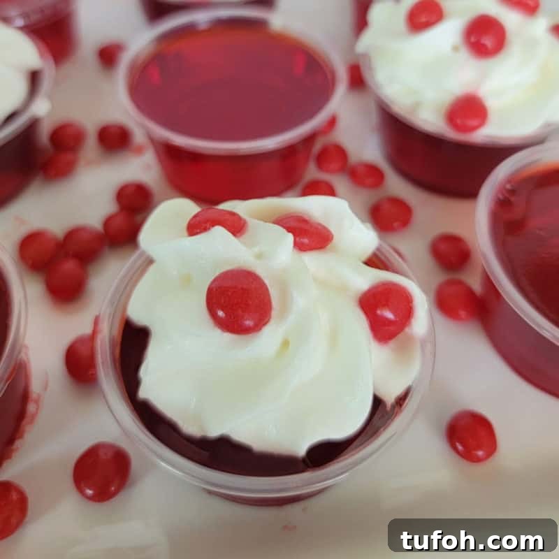 25+ Romantic Valentine's Day Cocktails and Toasting Drinks 23 Fireball Jello Shot with whipped cream and a red hot candy on a white plate